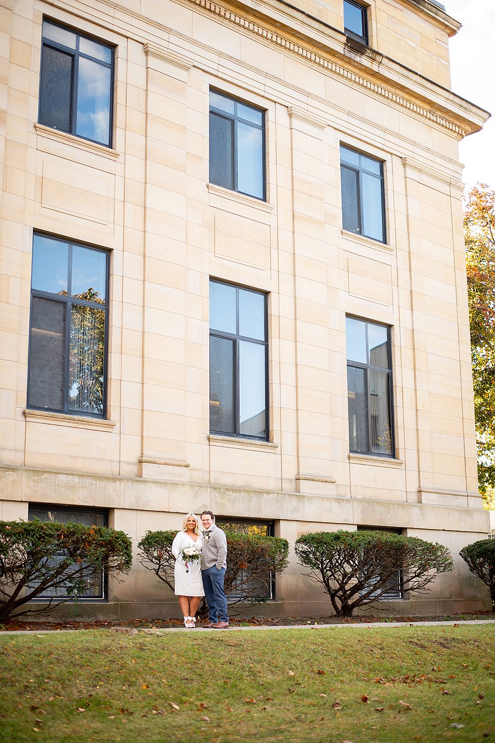 Elegant limestone building with classic architectural details and windows stands against autumn foliage.