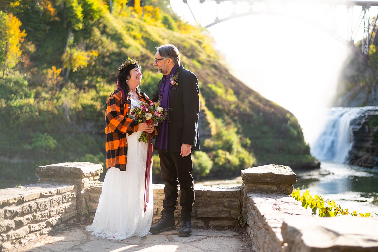 Two people share a romantic moment at Taughannock Falls State Park during a vibrant autumn sunset.