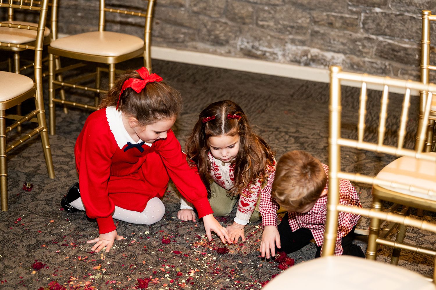Children in bright red and pink outfits playing and laughing on a stone floor.