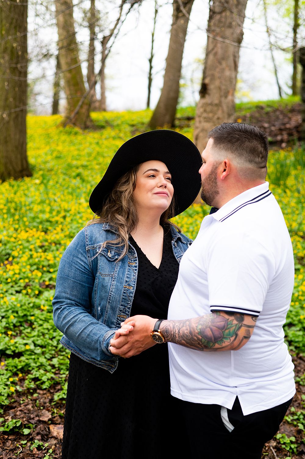 Romantic couple sharing a tender moment in a spring forest surrounded by yellow flowers and trees.