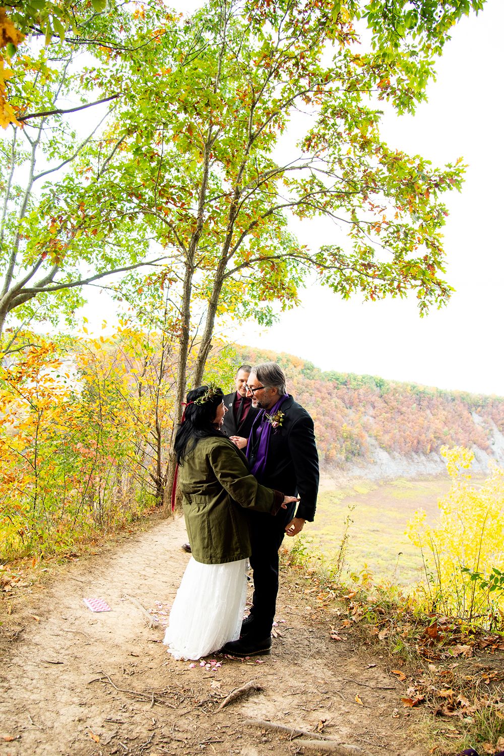 Couple sharing romantic moments on an autumn trail surrounded by golden foliage and falling leaves in nature.