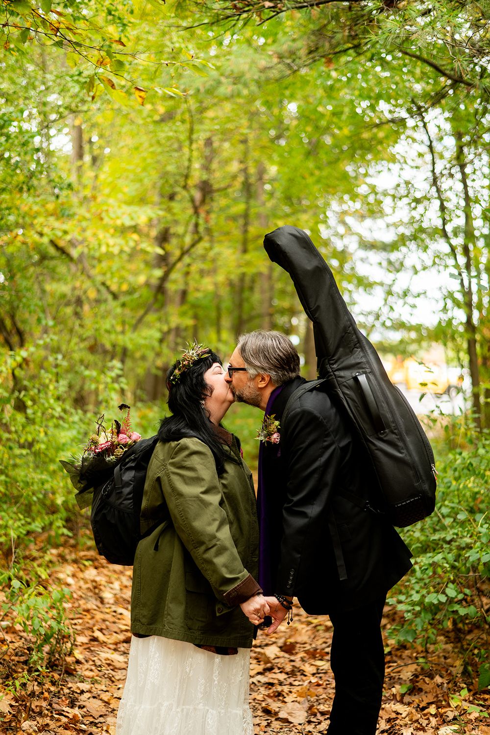 A romantic couple dancing and dipping amidst autumn leaves in a wooded area.