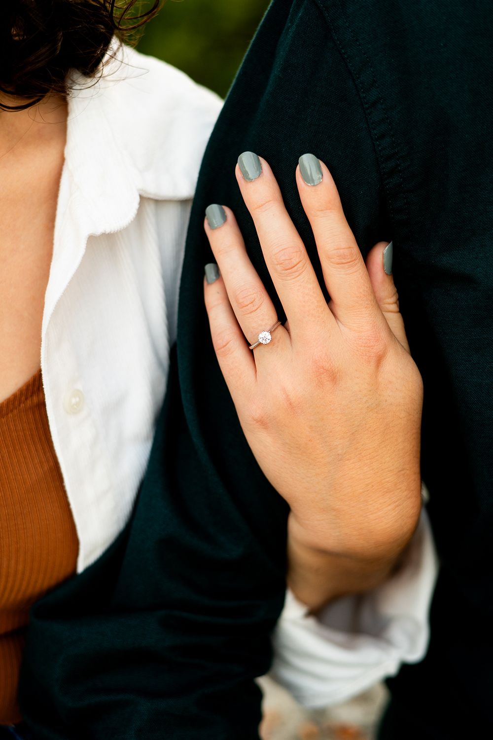 Three close-up images of hands wearing a white sleeve showing off a sparkling engagement ring.