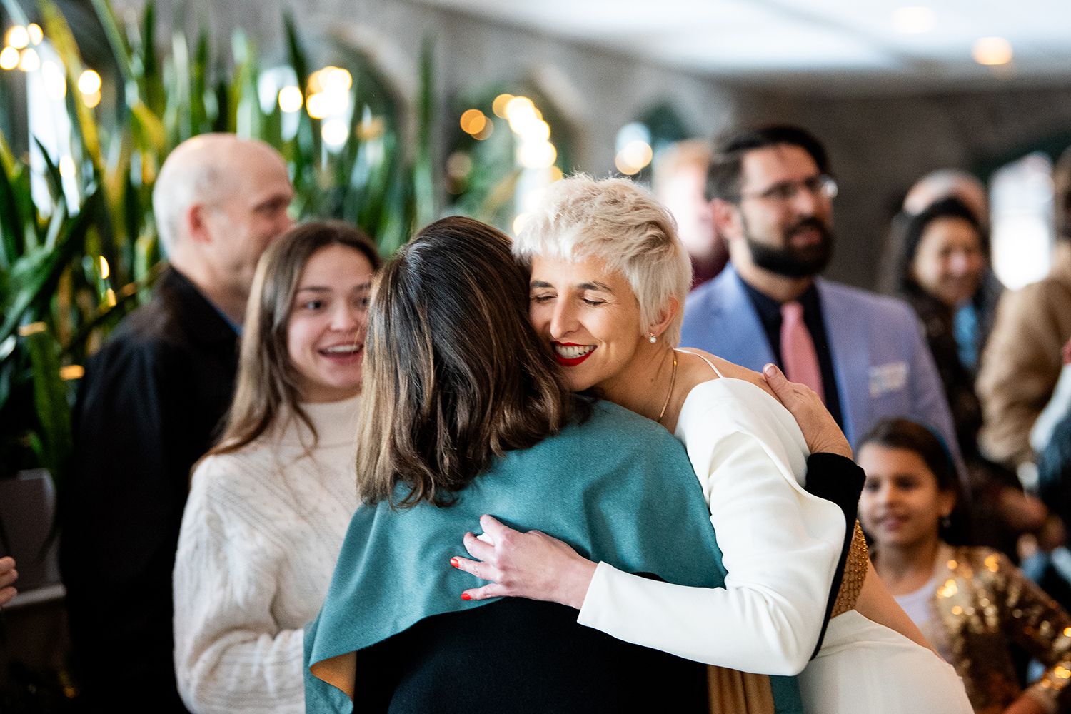 People gathered at a social event sharing warm embraces and conversations.