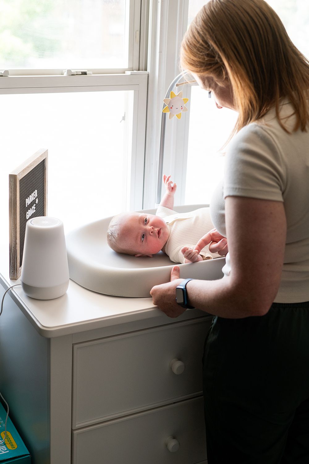 A changing table scene by a window with a letterboard and white humidifier on the surface.