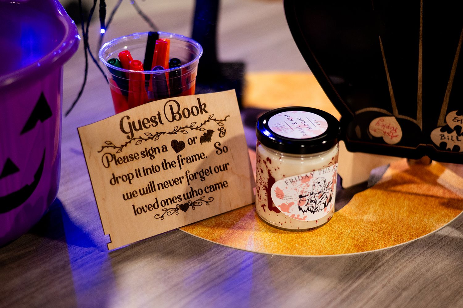 Guest book and decorative jar displayed on wedding reception table with purple ambient lighting and decorative elements.