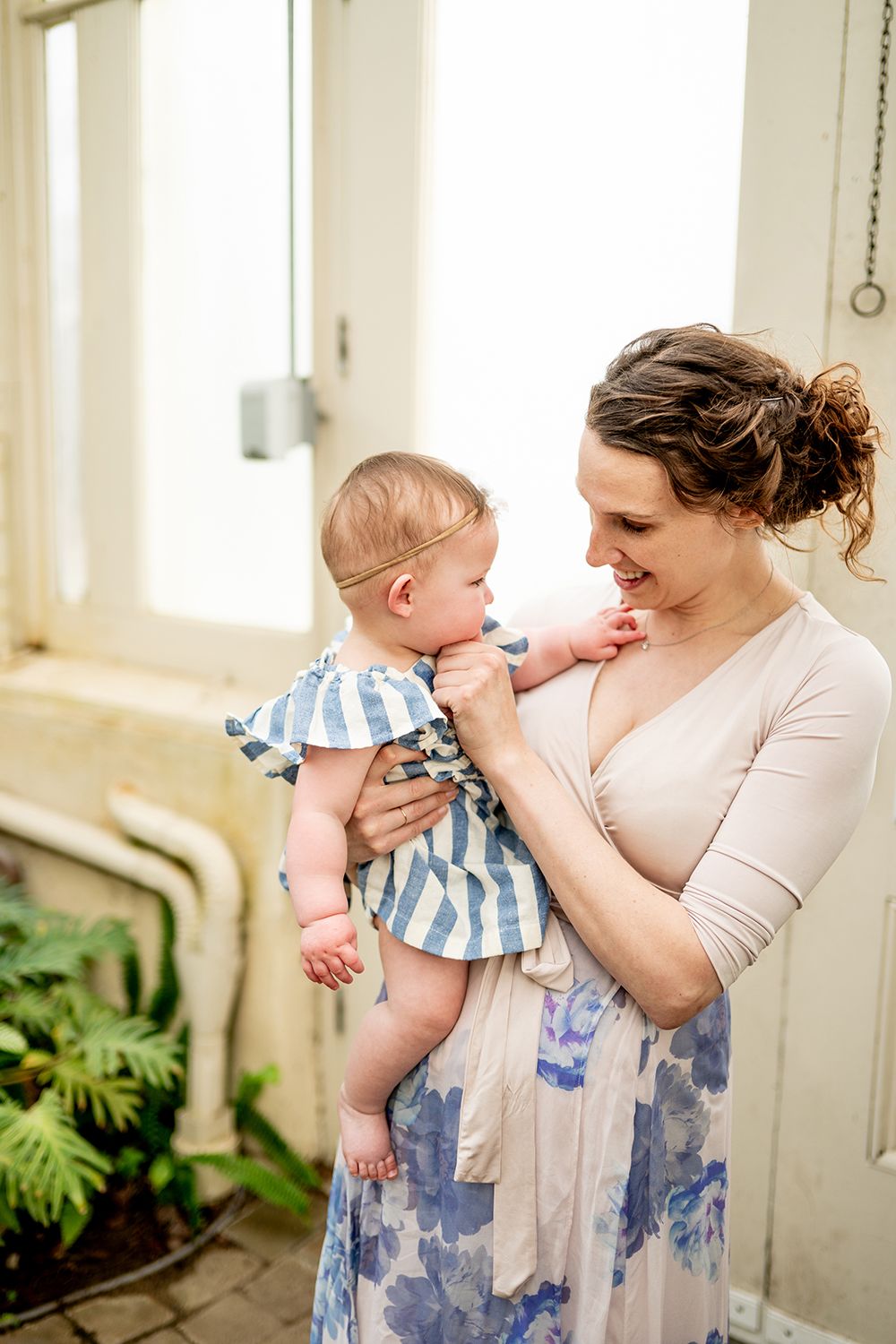A tender moment between caring parent and young child wearing blue and white striped outfit on a porch.