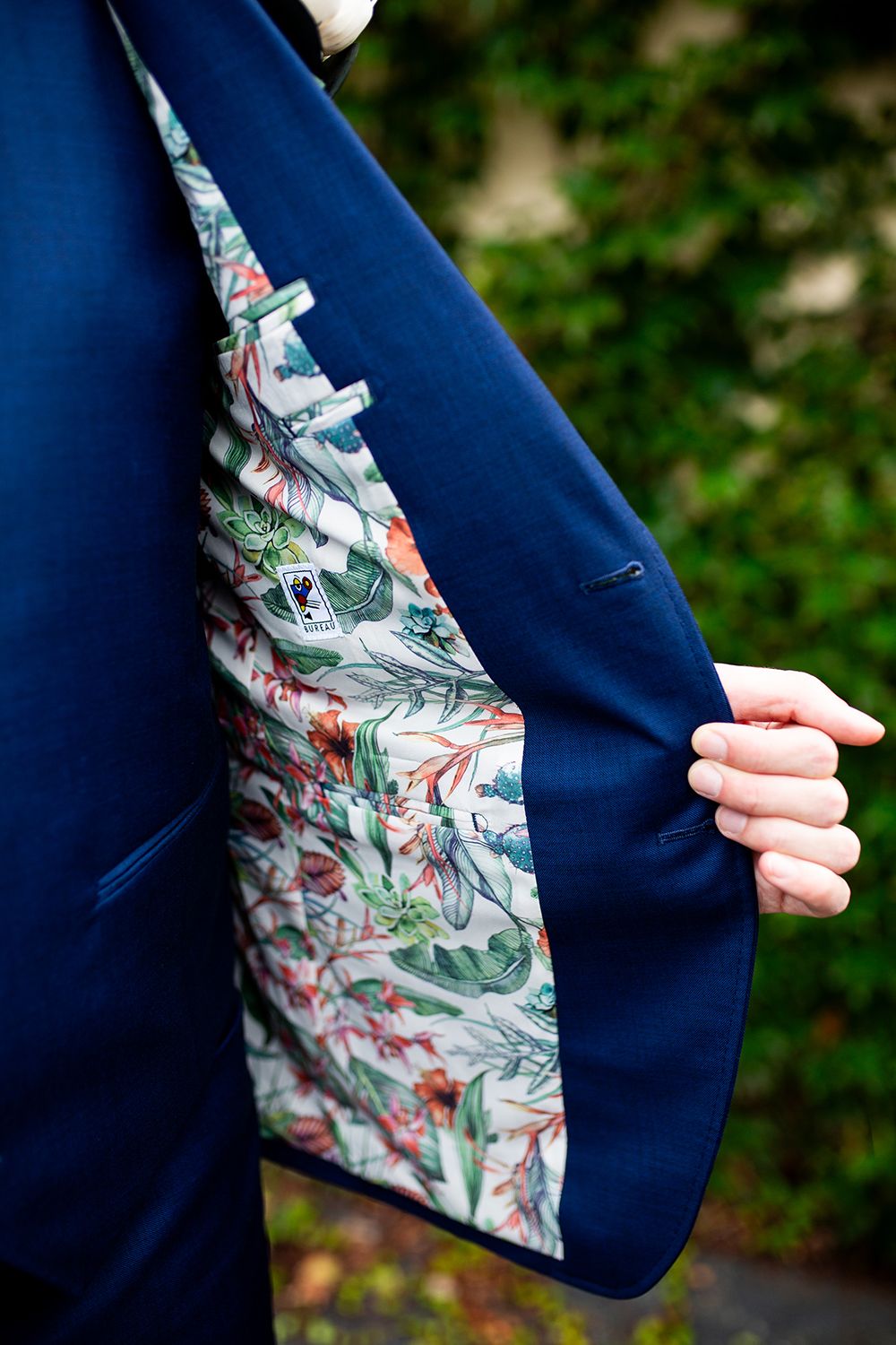 Close-up details of a navy suit jacket with floral patterned lining showing through the sleeve.