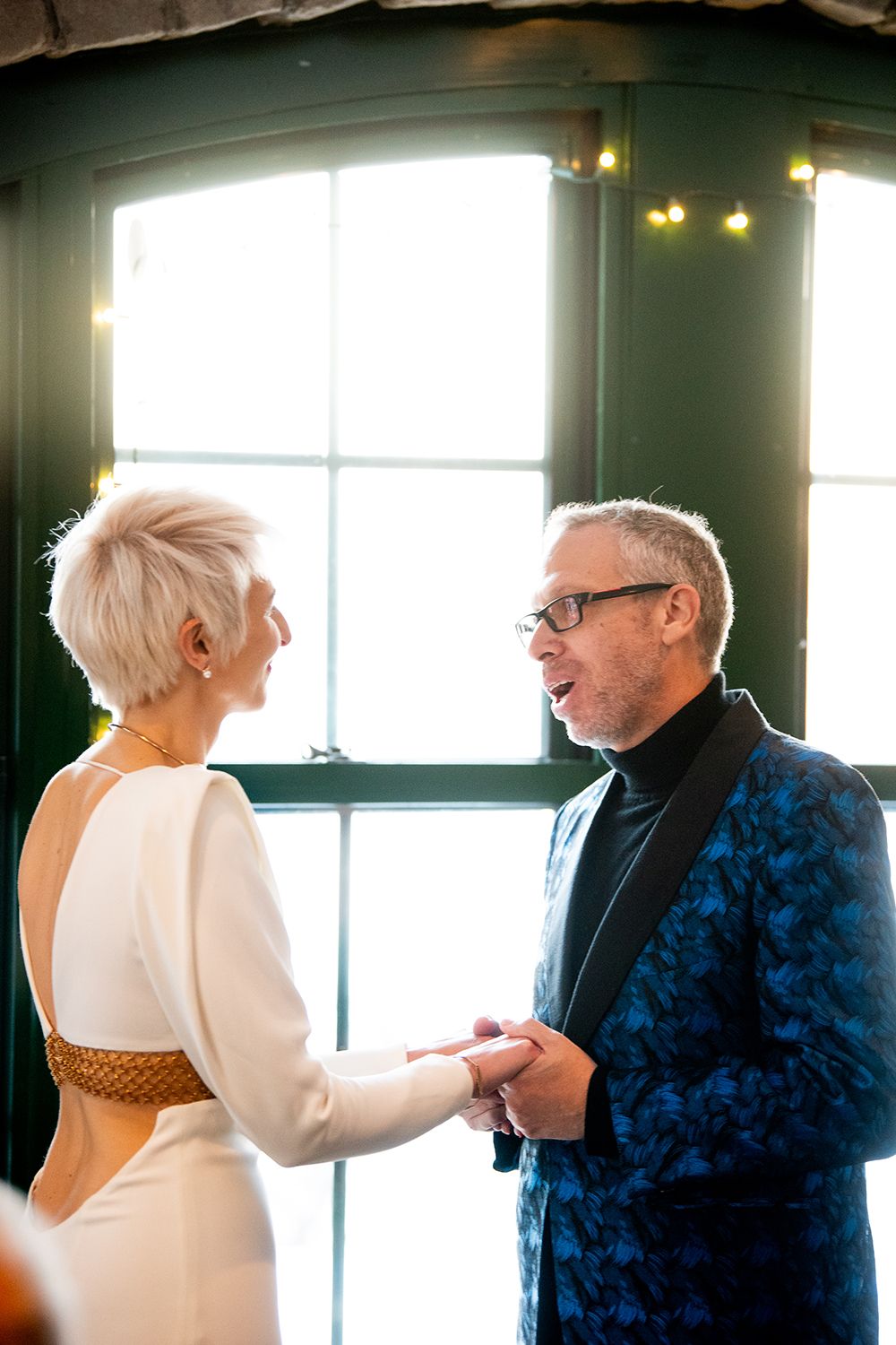 A sequence of candid moments between two people in formal attire conversing intimately near a bright window.