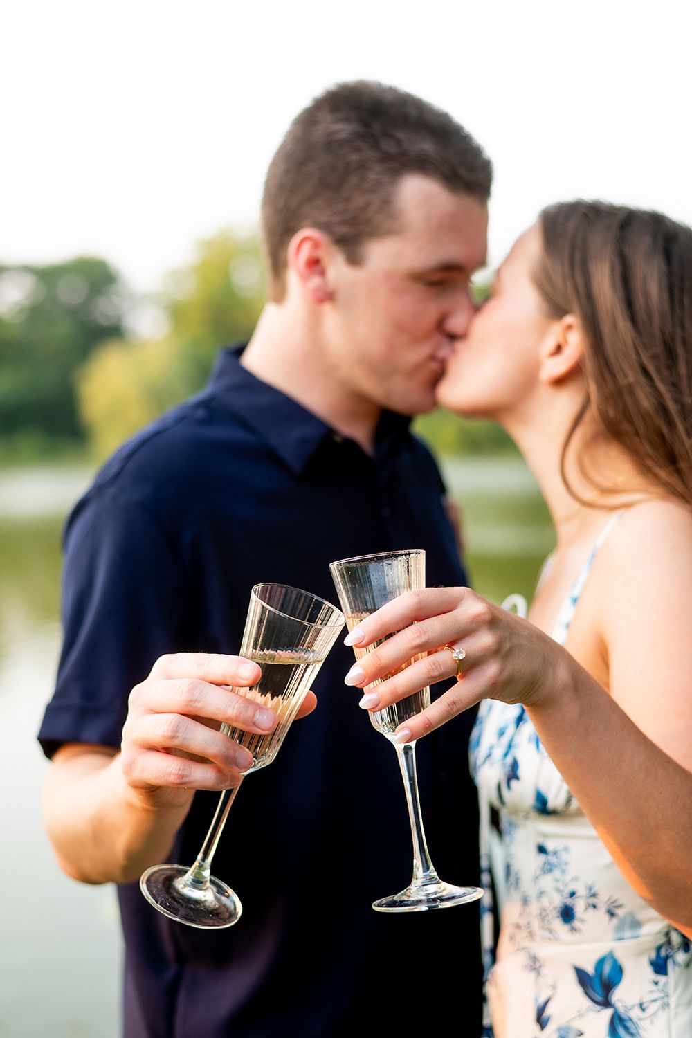 A romantic couple shares champagne and kisses by the waterfront in multiple photos.