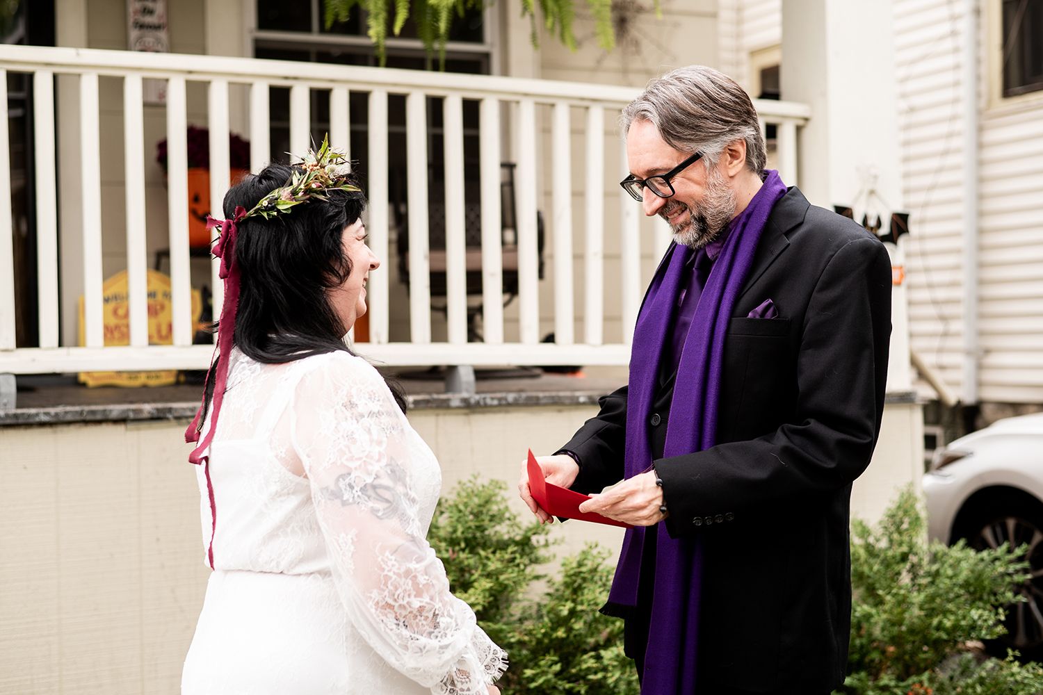 A tender moment between newlyweds during an outdoor ceremony with white porch railings in the background.