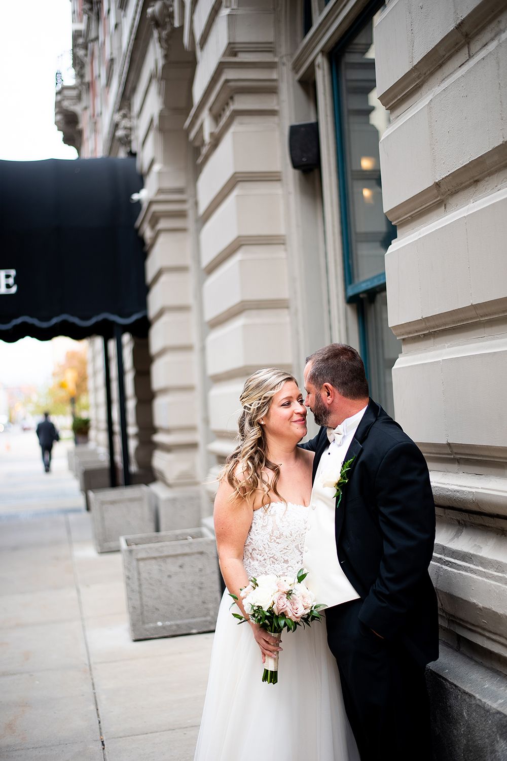 A romantic wedding couple shares tender moments on urban steps in a series of black and white photographs.