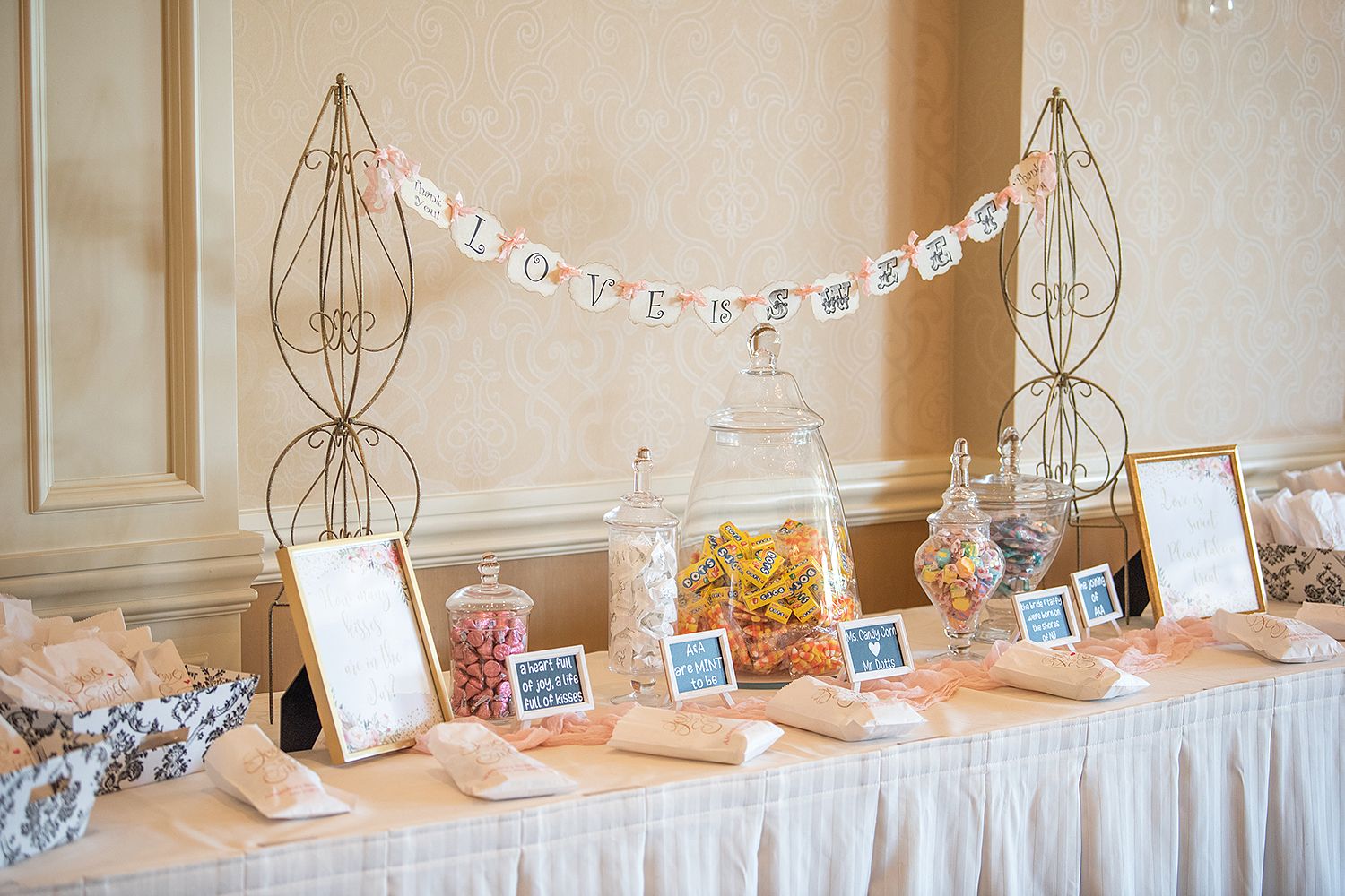 Elegant wedding gift table decorated with wire decor, banners, and small signs in a cream-colored space.