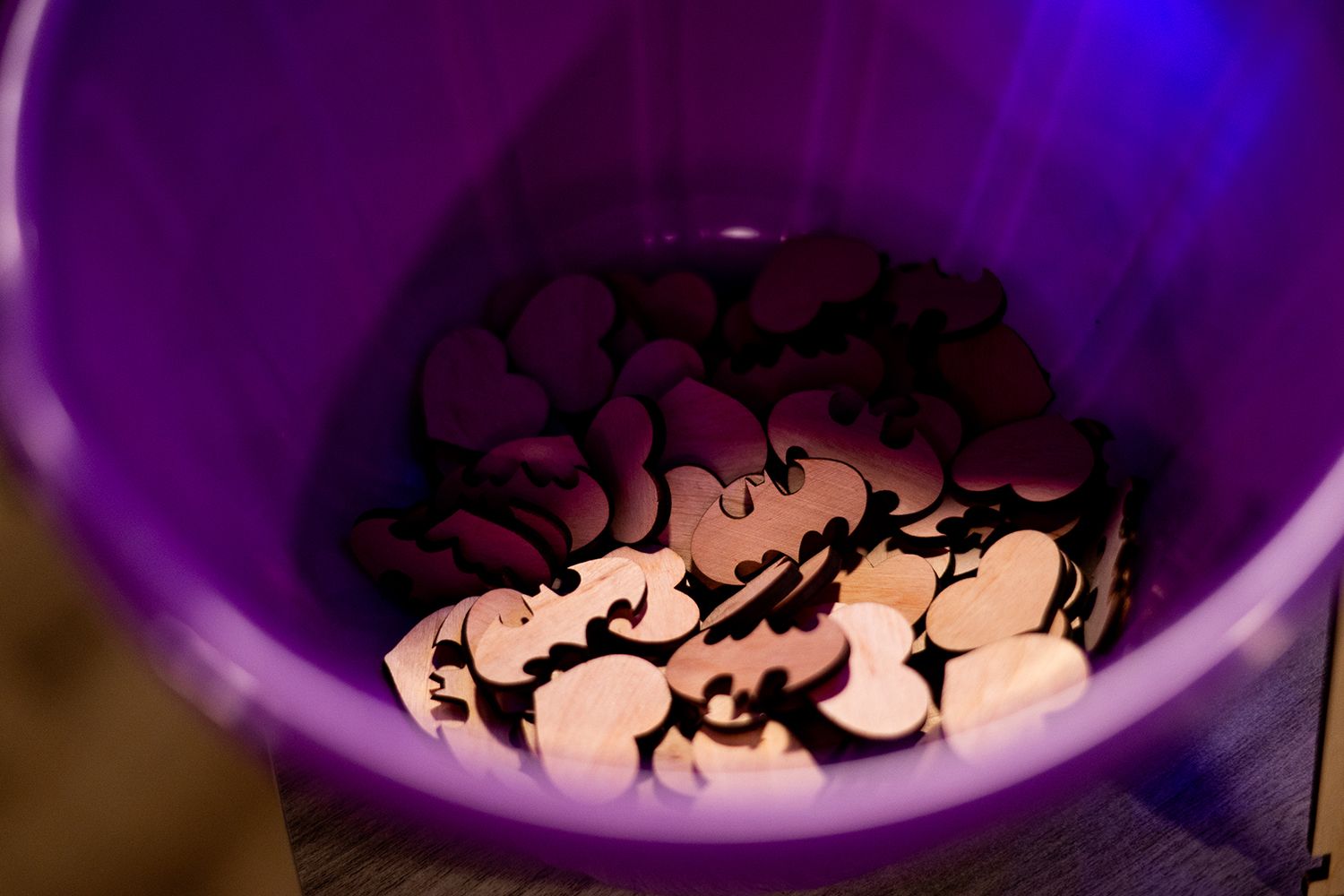 Halloween decorations shaped like spiders sit in a purple plastic bucket under blue lighting.