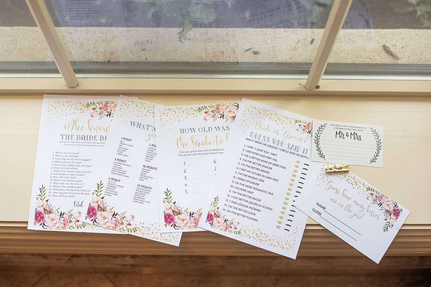 Wedding invitation cards with floral designs and details displayed on a rustic wooden surface.