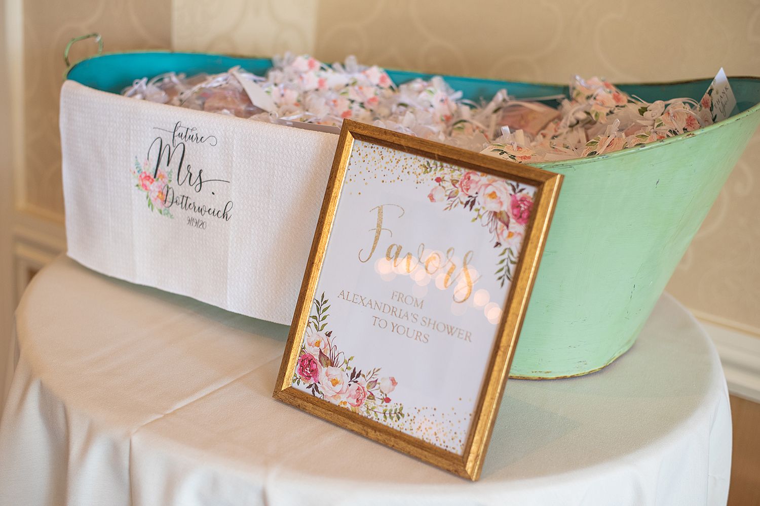 Wedding stationery with pink floral designs laid out on a beige table surface with gold frames.