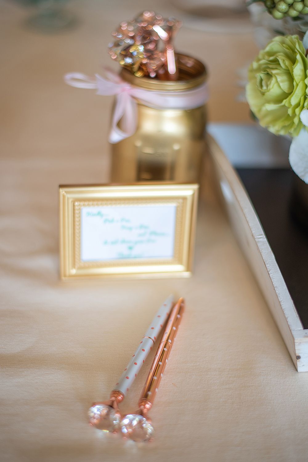 Pink and gold decorative mason jar with sparkly lollipops and small gold frame on table.