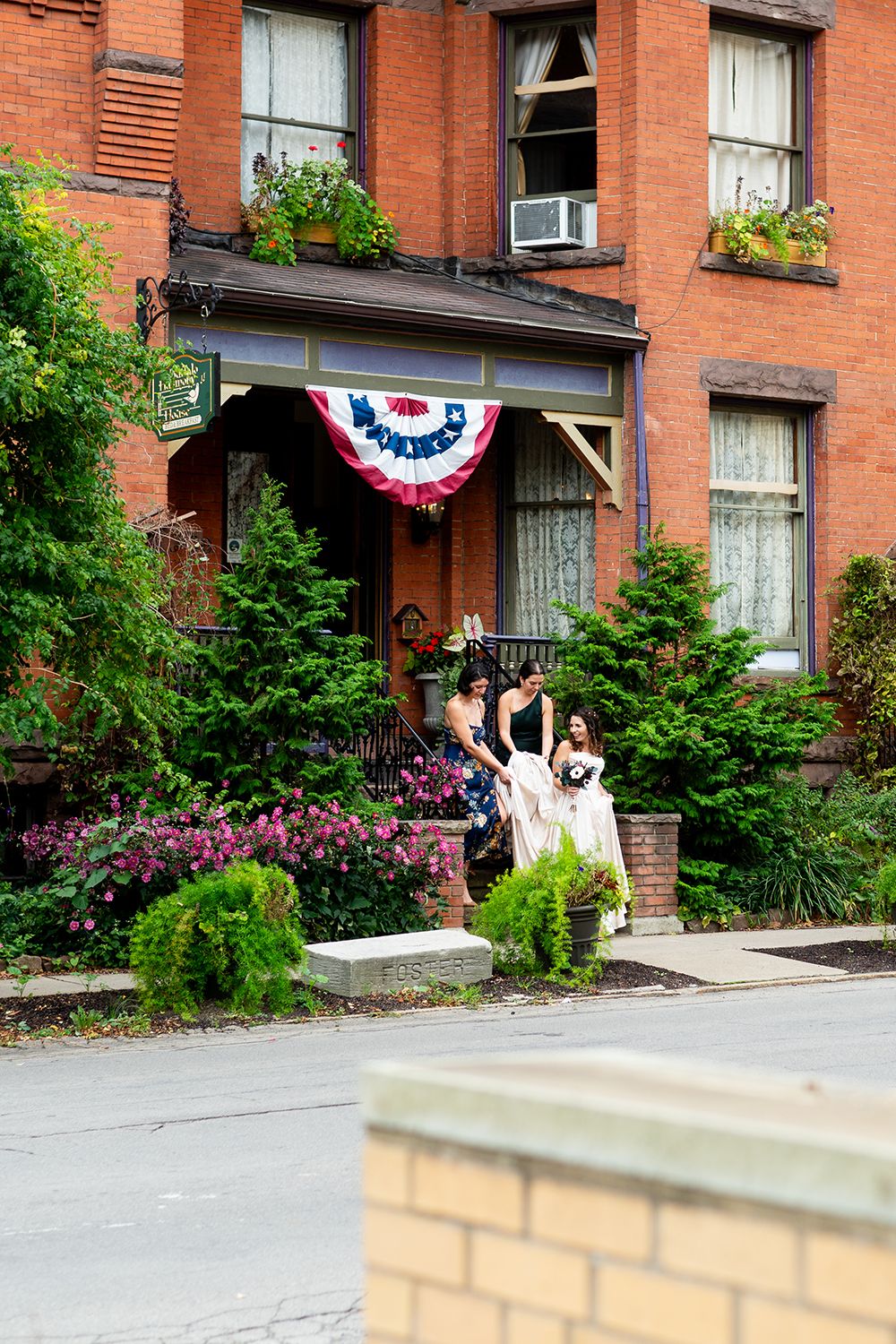 Red brick historic house with patriotic bunting and flower boxes decorating the front entrance.