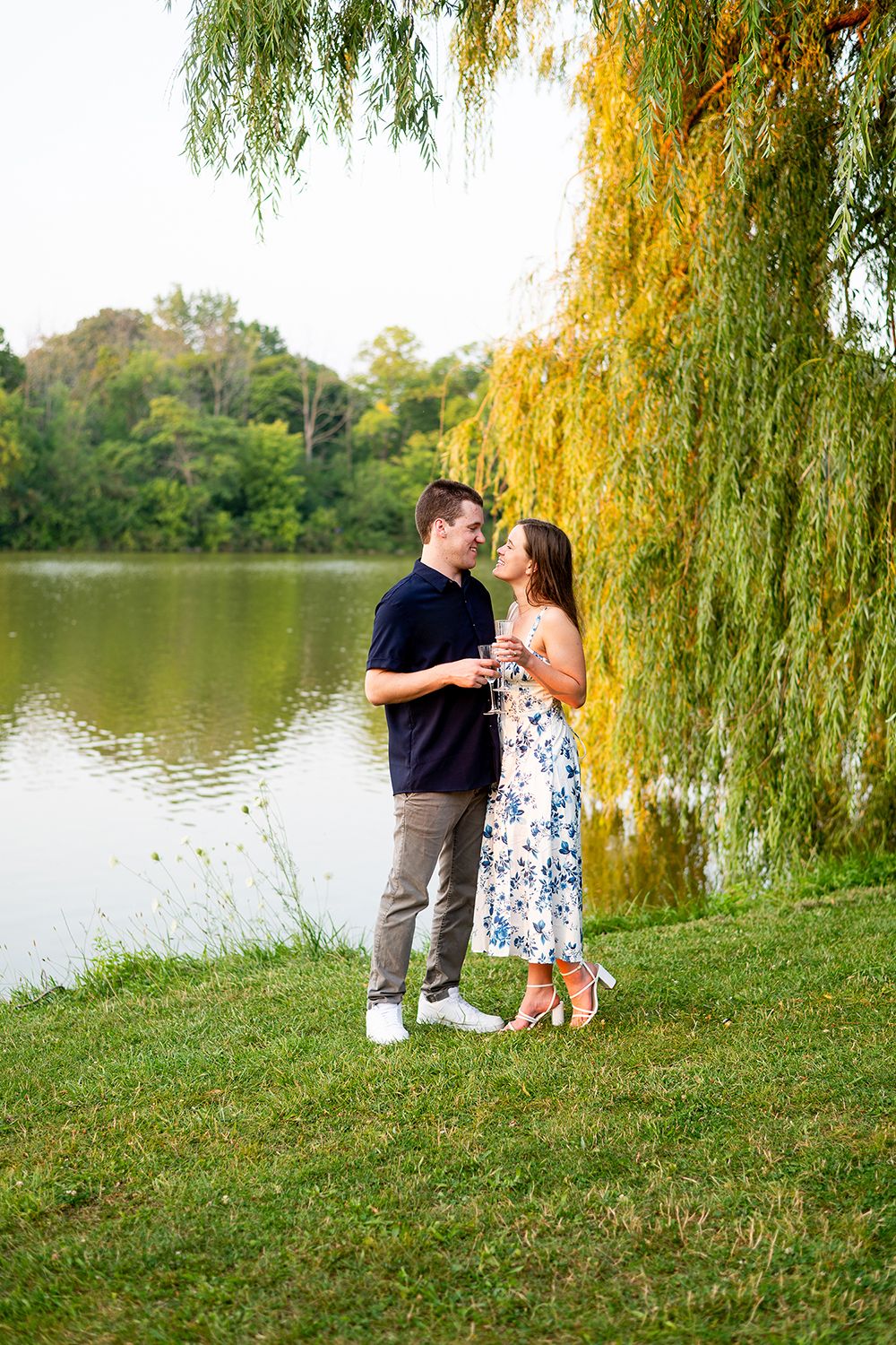 A romantic scene unfolds beneath a weeping willow tree by a serene lake in autumn.