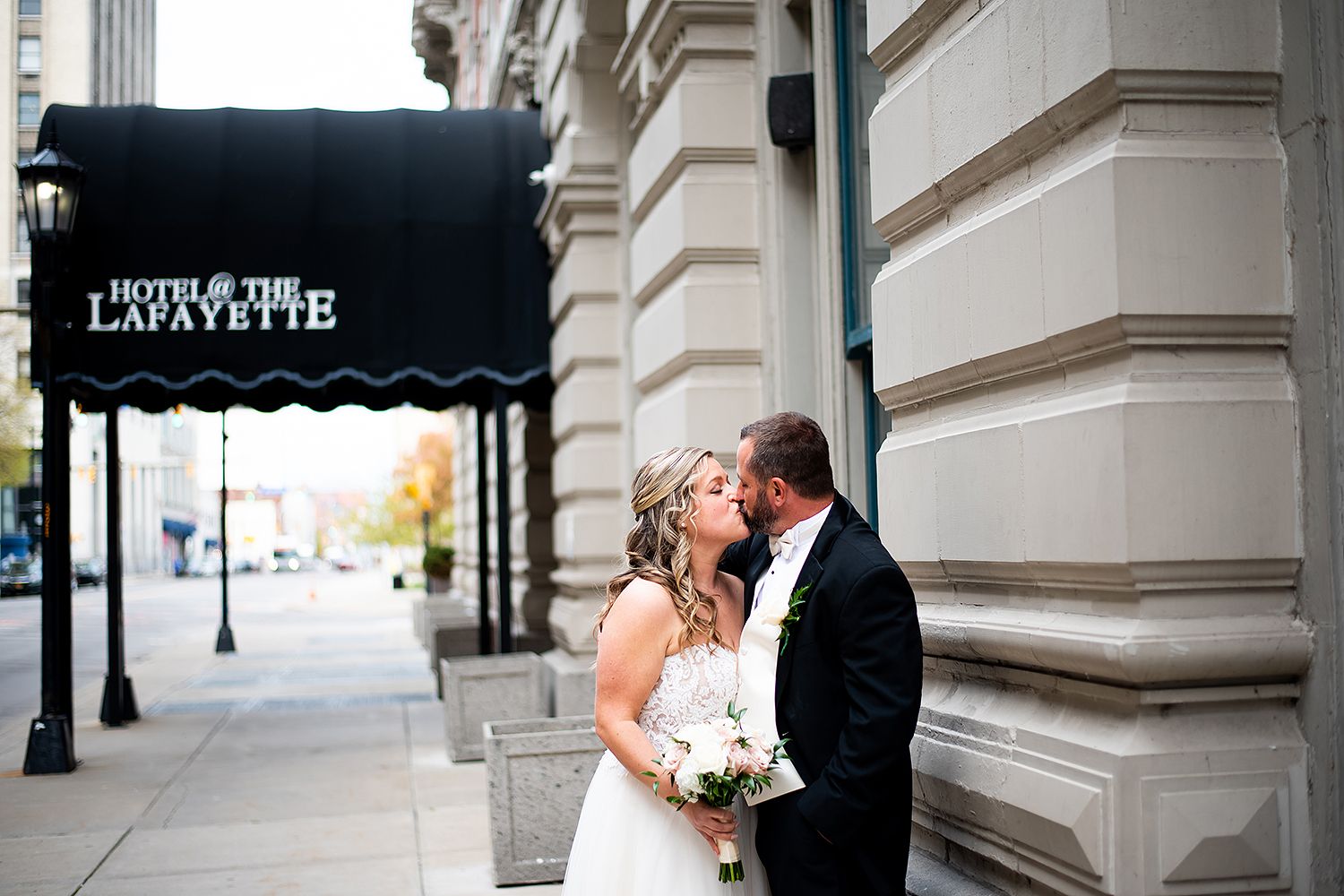 A couple embraces and shares a romantic moment together during their wedding in front of a grand architectural backdrop.