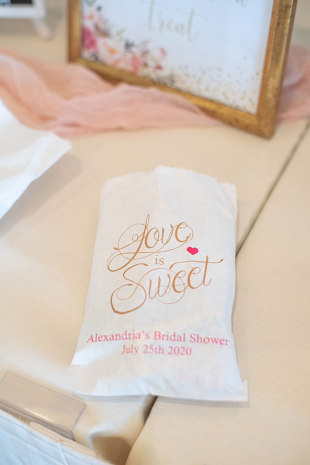 White paper favor bag with gold 'Love is Sweet' text and customized bridal shower details.