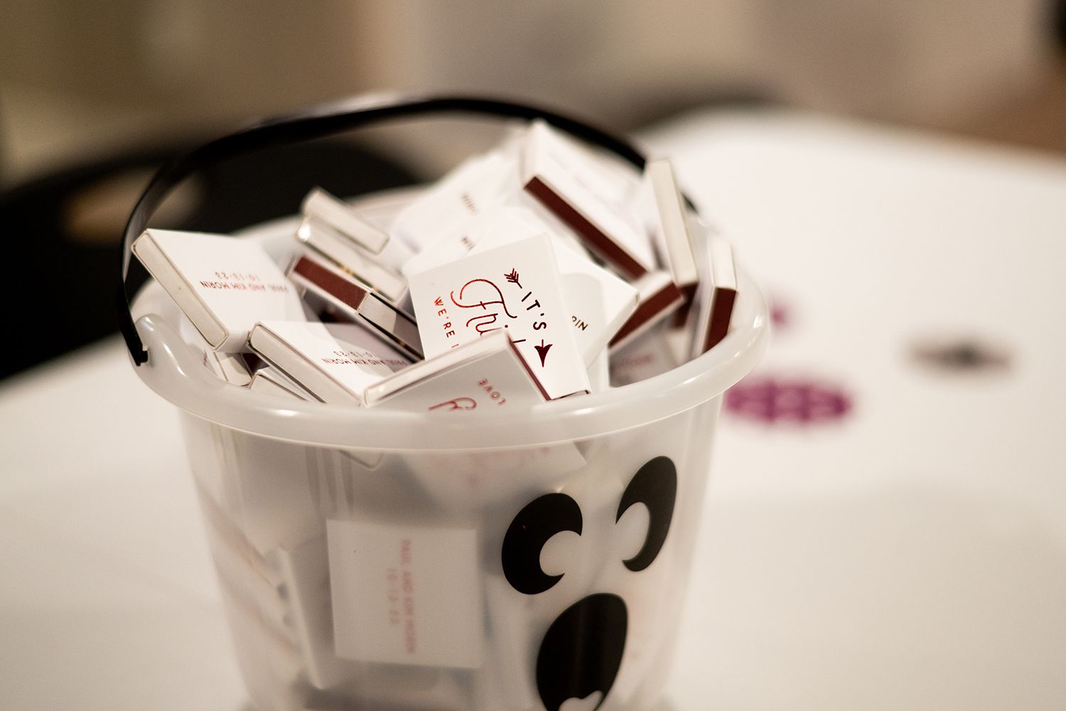 Close-up of paper slips in a white plastic cup with a smiley face drawn on it.
