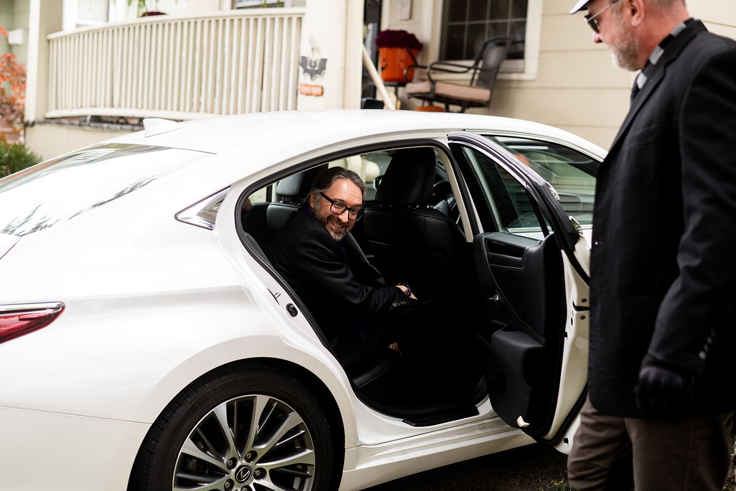 Wedding couple getting into a white luxury car while smiling and celebrating their special day.