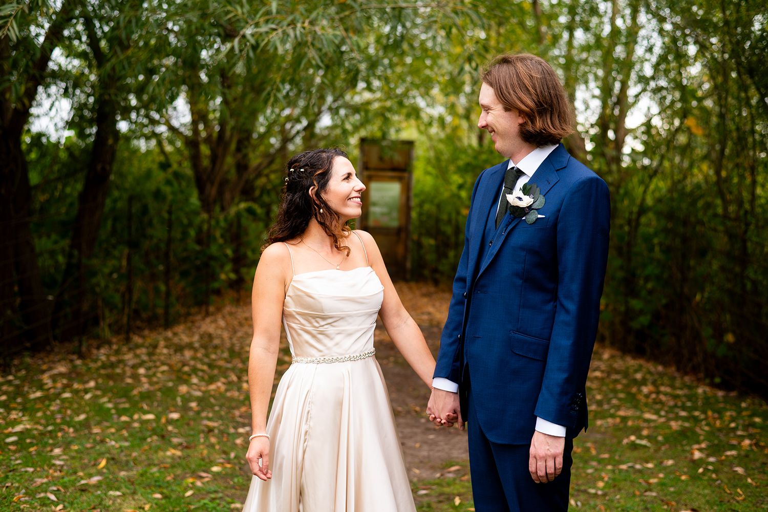 Couple shares intimate moment on garden path wearing elegant wedding attire.