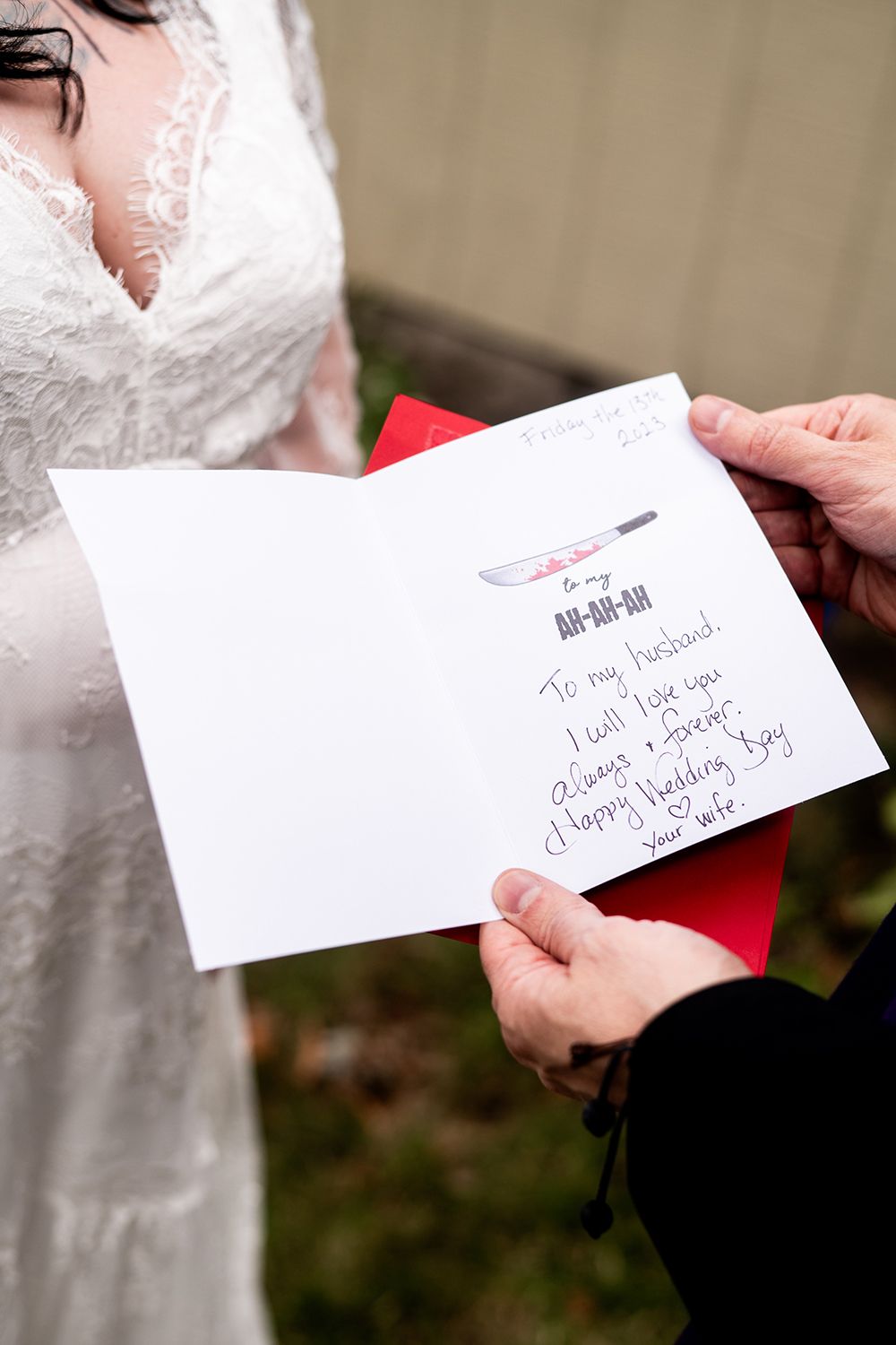 Close-up view of hands holding white wedding invitation cards with handwritten letters.