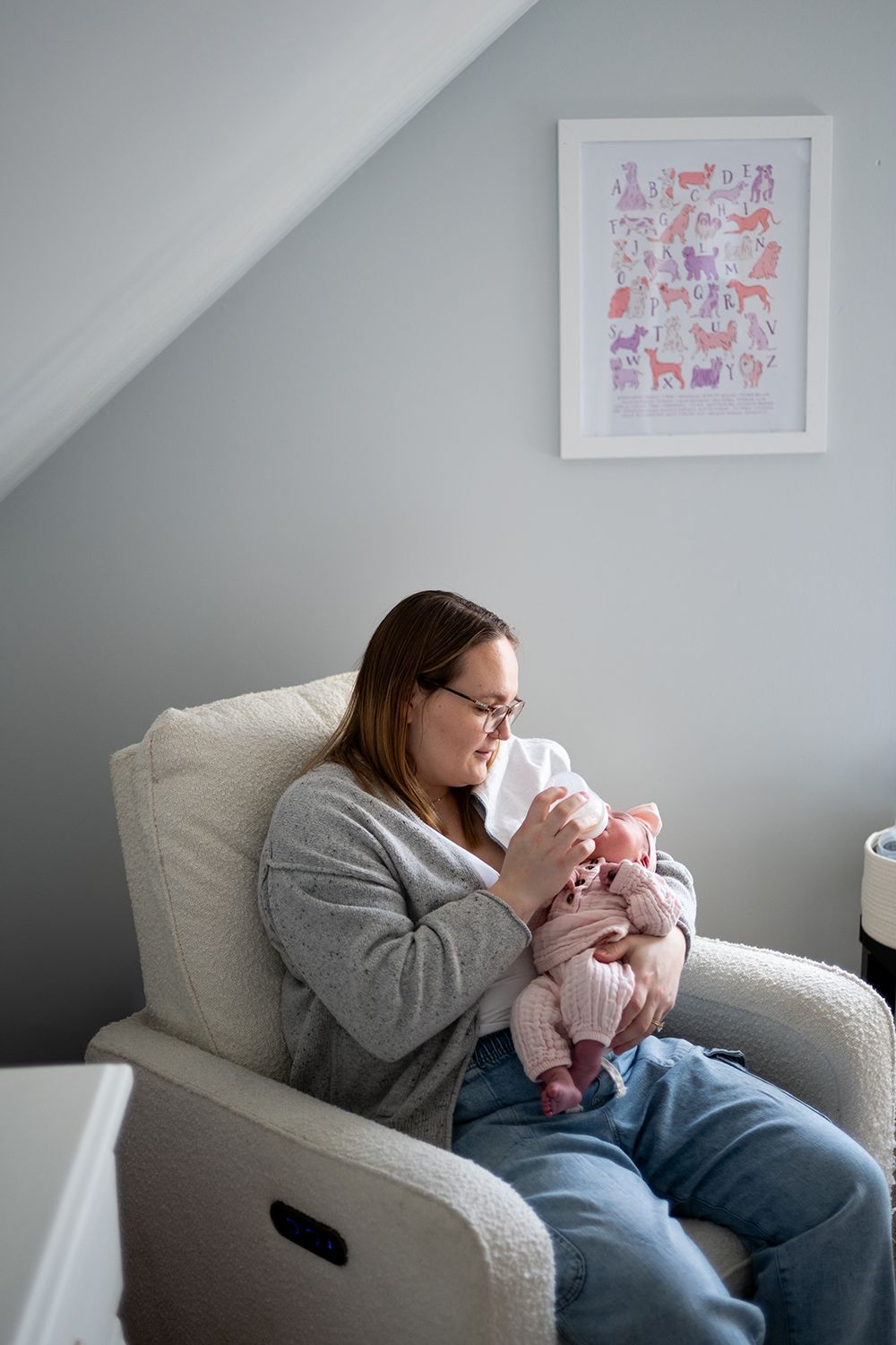 Tender moment being shared with a newborn baby in a cozy white armchair under soft natural light.