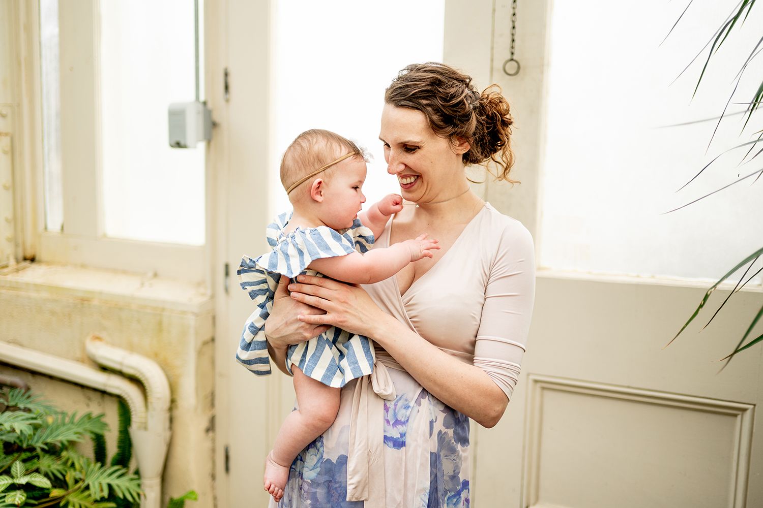 A tender moment between parent and child in a sun-lit room with white decor and natural lighting.