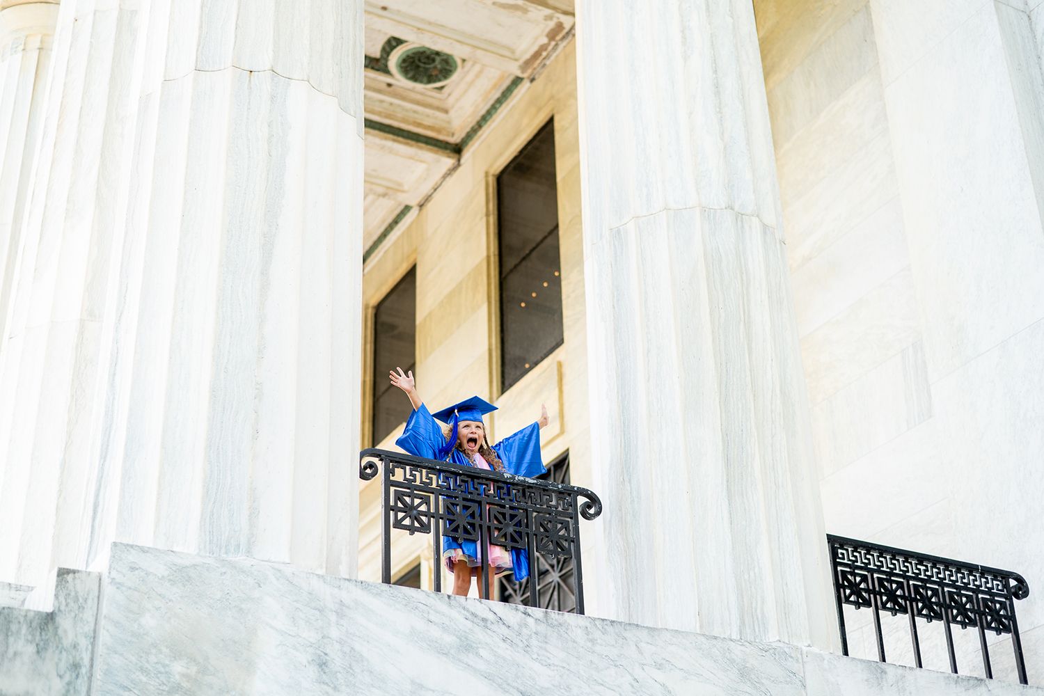 Grand white columns line a historic building entrance with ornate iron railings on the upper balconies.