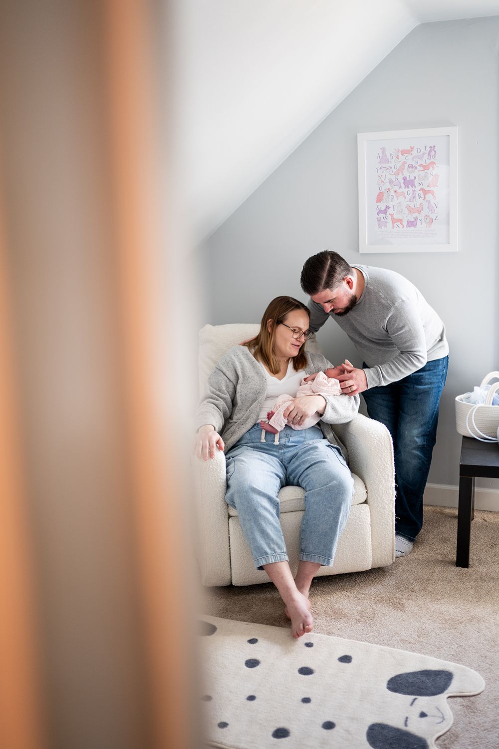 Family gathering in cozy living room with white furniture and polka dot rug during intimate moment.