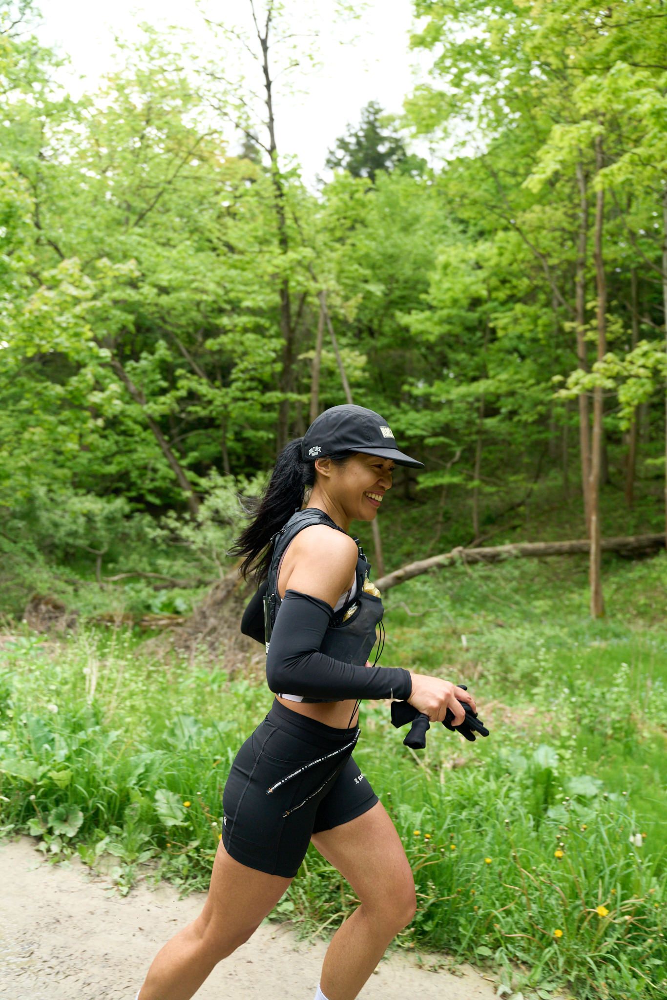 A woman runs along a road, with trees lining the path in the background.