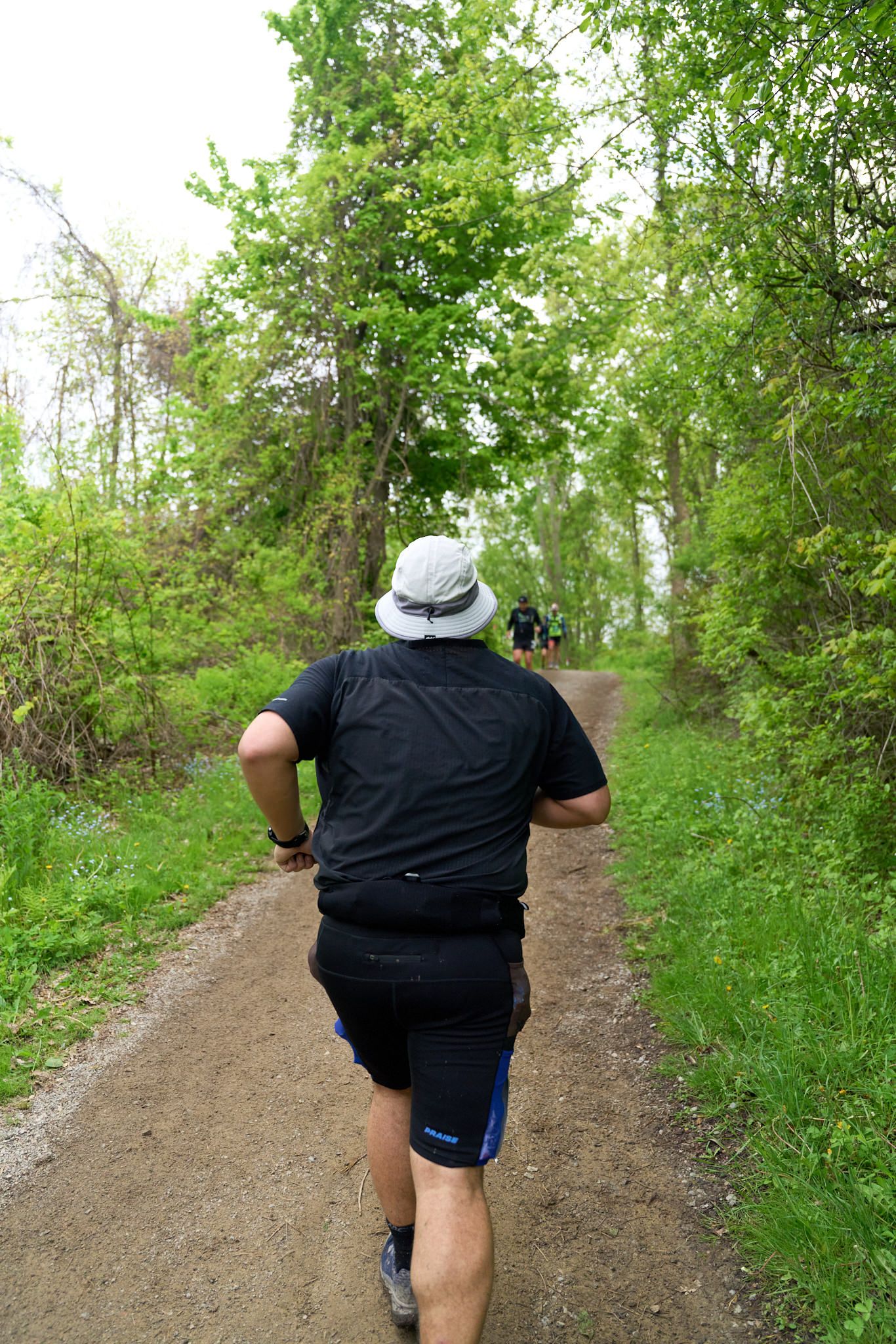 A man running along a wooded path, showcasing a vibrant green forest backdrop.