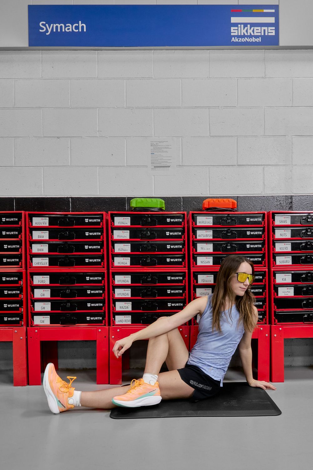 A woman sits cross-legged on the floor, facing a vibrant red storage unit, looking relaxed and at ease in the space.