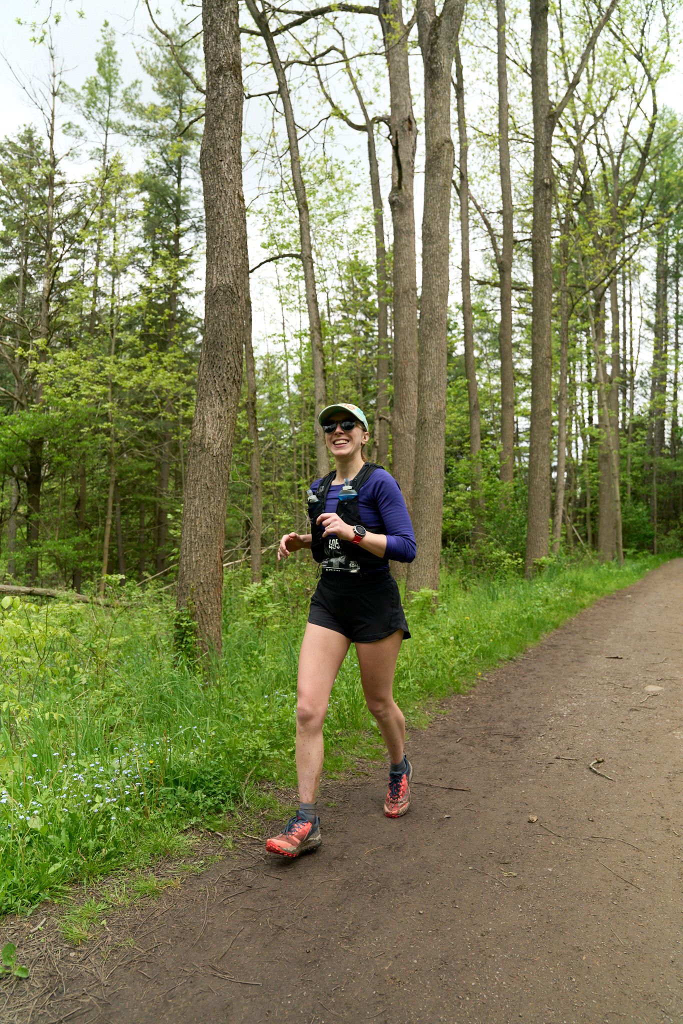 A woman is seen running on a road, carrying a backpack, with a scenic landscape in the background.