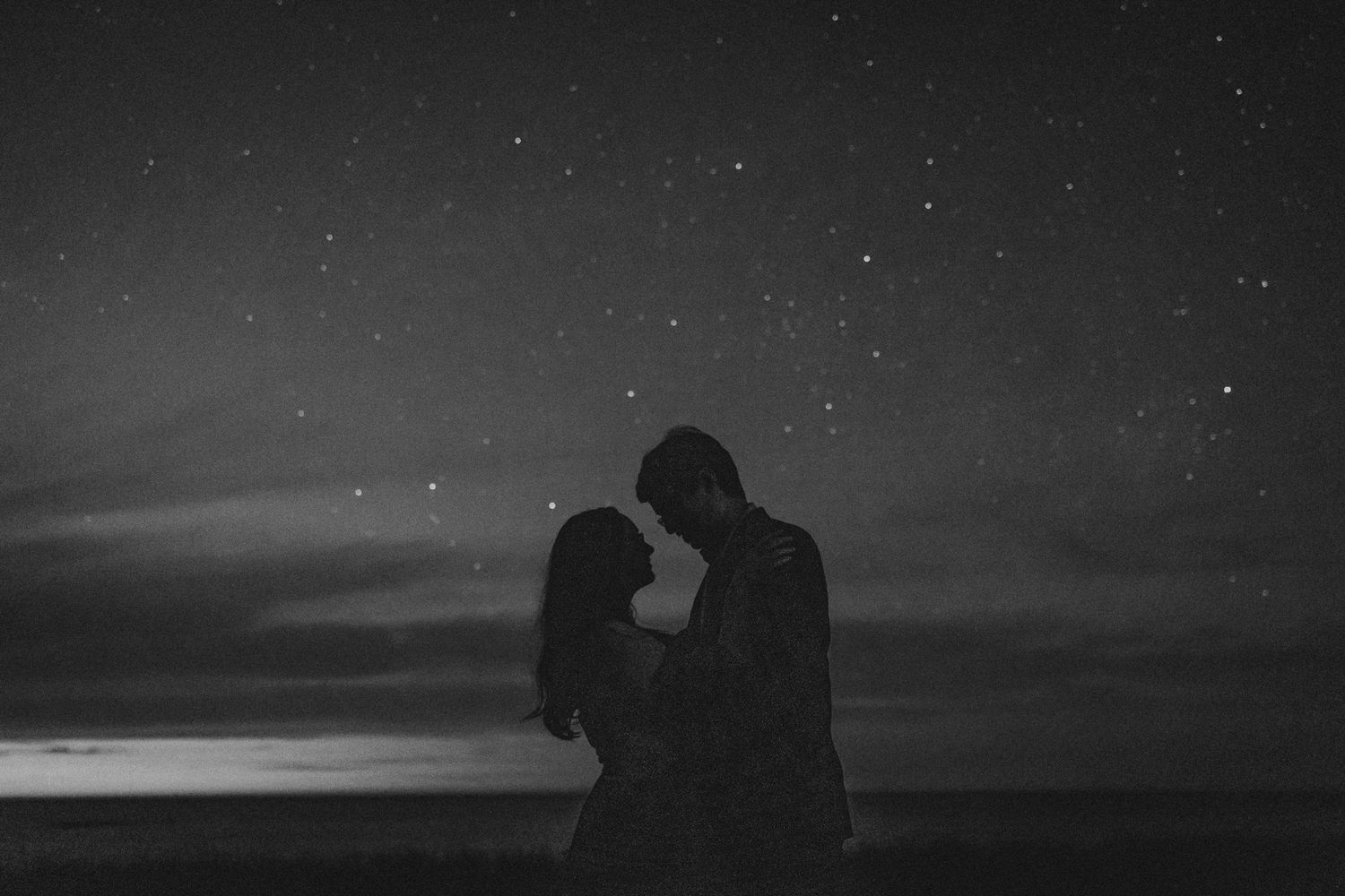 Dark black and white silhouettes of people on beach at sunset with split frame montage effect.