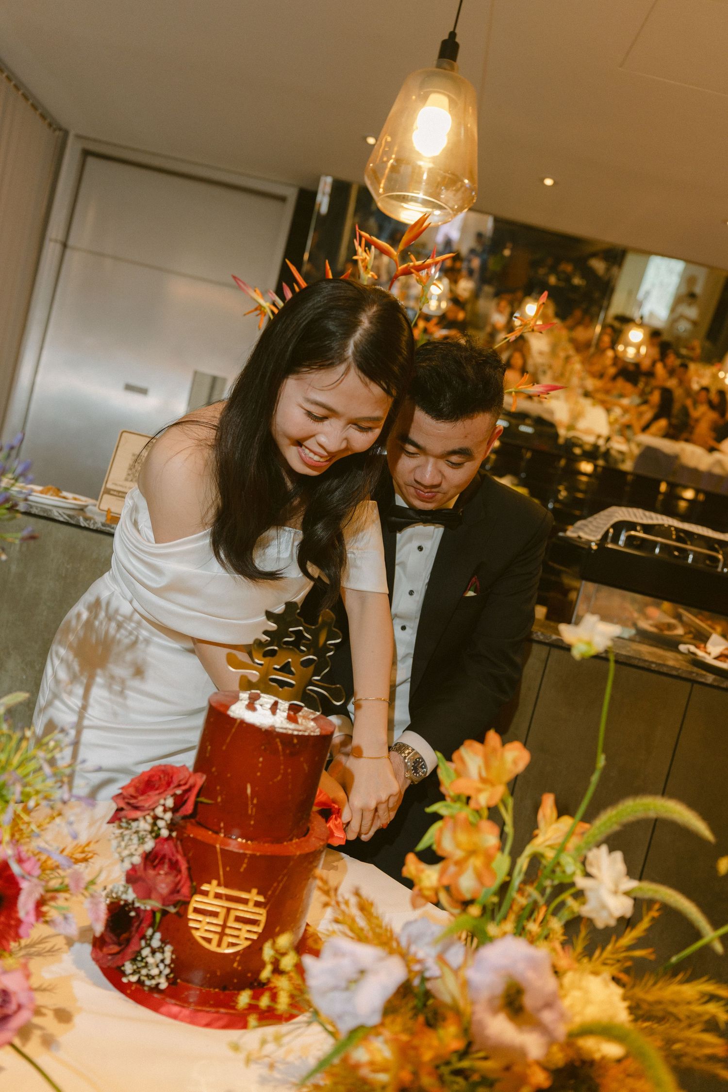 Traditional Asian wedding ceremony tea ritual with bride and groom pouring tea at elegantly decorated banquet table.