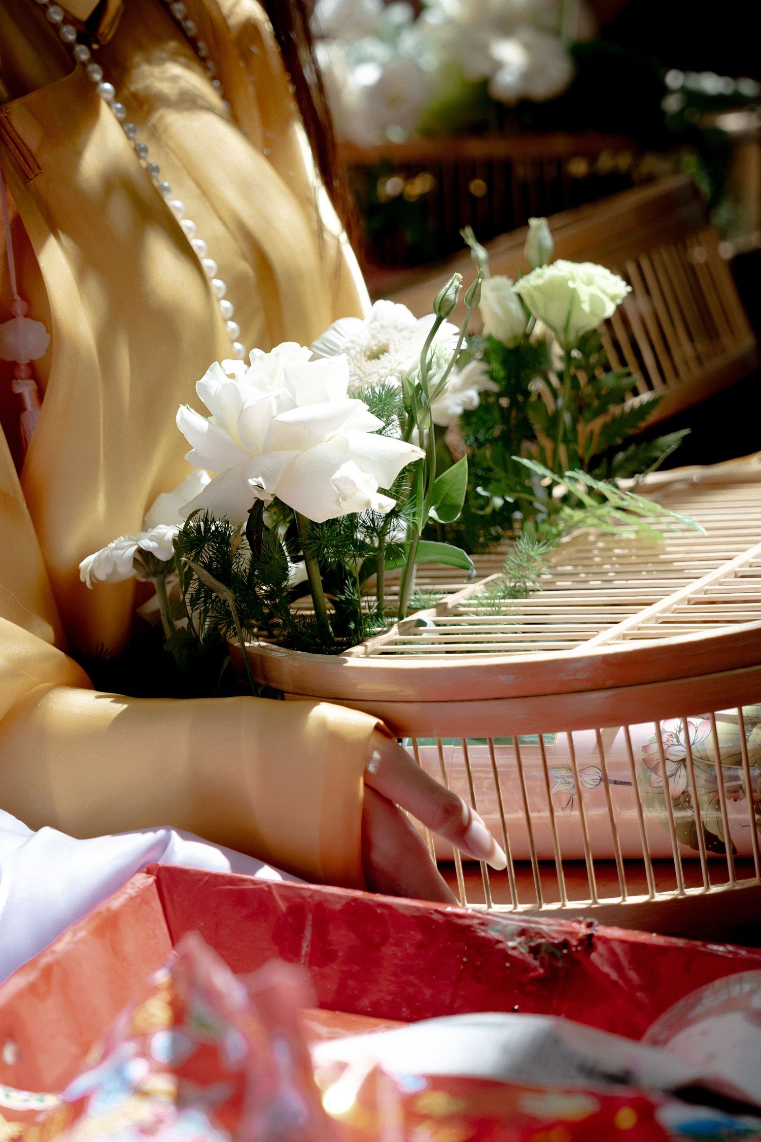 White carnations and flowers decorate a traditional wooden instrument being played in sunlight.