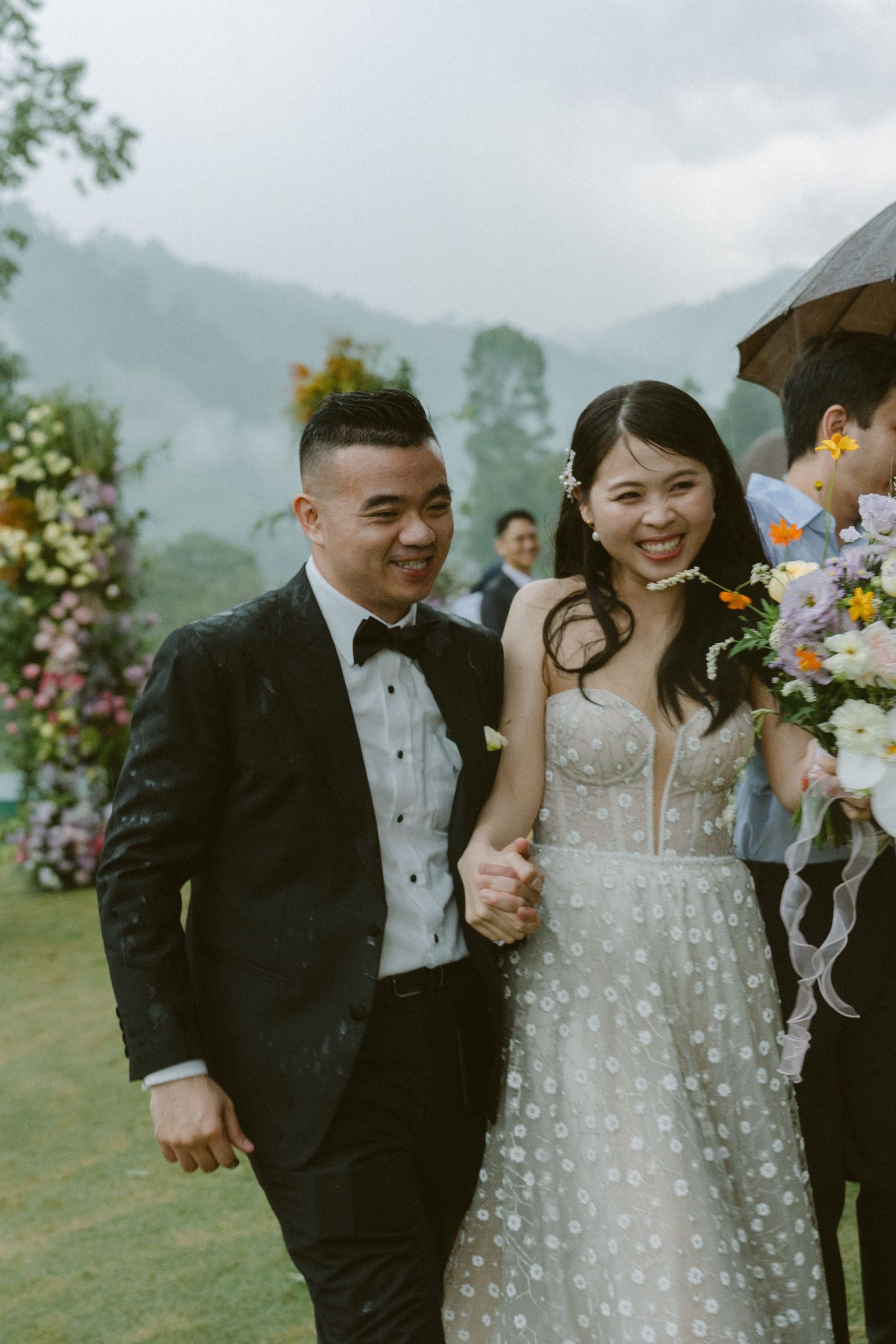 A couple shares a joyful moment at their outdoor wedding ceremony with misty mountains in the background.