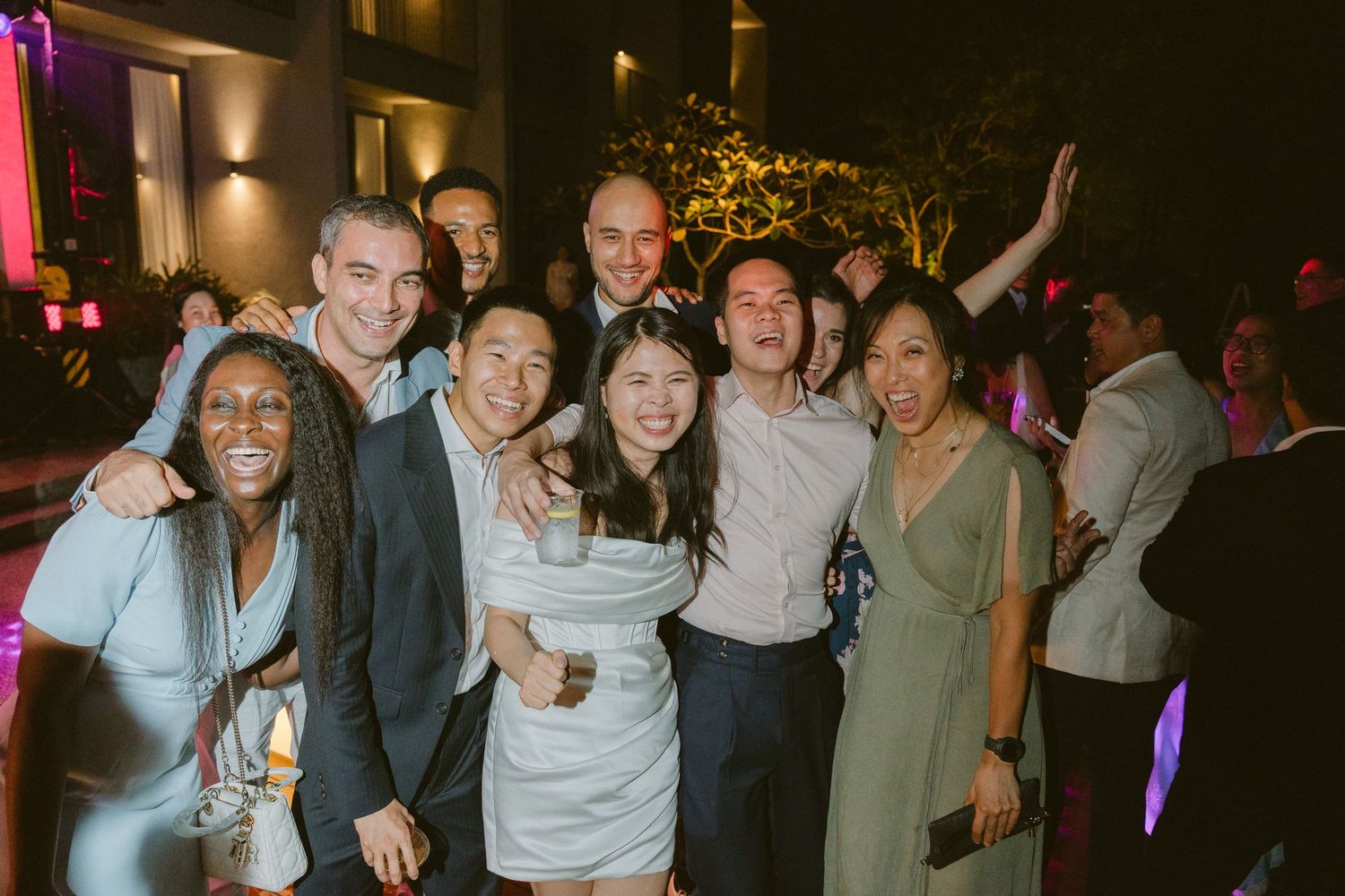 A group of friends celebrating at a nighttime party venue with colorful lighting and festive atmosphere.