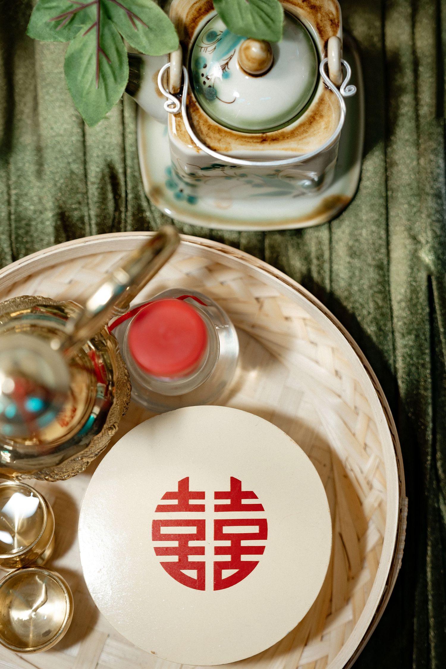 Traditional Chinese double happiness symbol on a plate with tea service and glassware on a green surface.