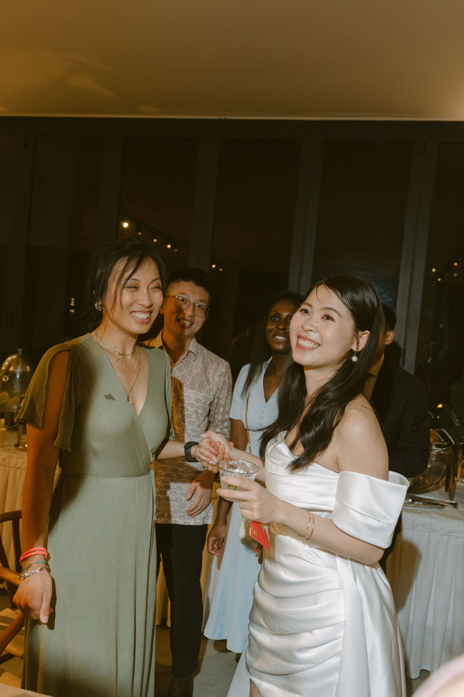 Guests enjoy a celebratory moment at an evening wedding reception with warm lighting and decorative white linens.