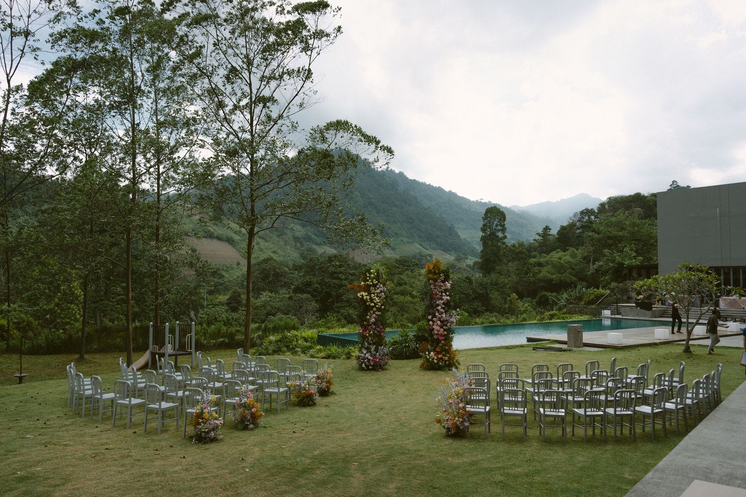 Chairs set up for an outdoor mountain wedding ceremony with a scenic backdrop of lush green hills and trees.