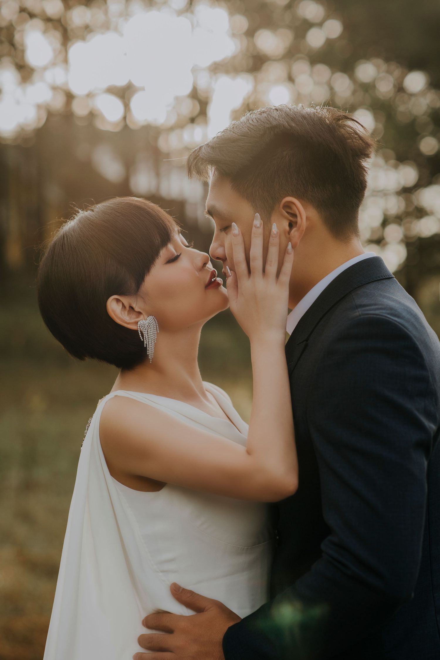 A romantic wedding couple sharing an intimate moment at sunset with soft bokeh lighting in the background.