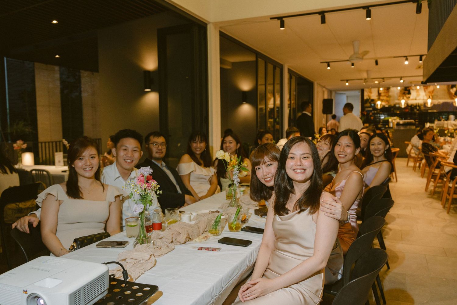 A group of people seated at a long dining table in a warmly lit restaurant during an evening celebration.