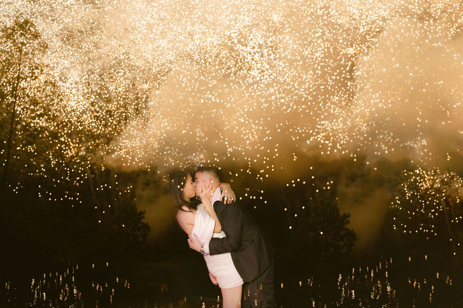 Dancing silhouettes illuminated by golden sparklers create a magical scene during an evening celebration.