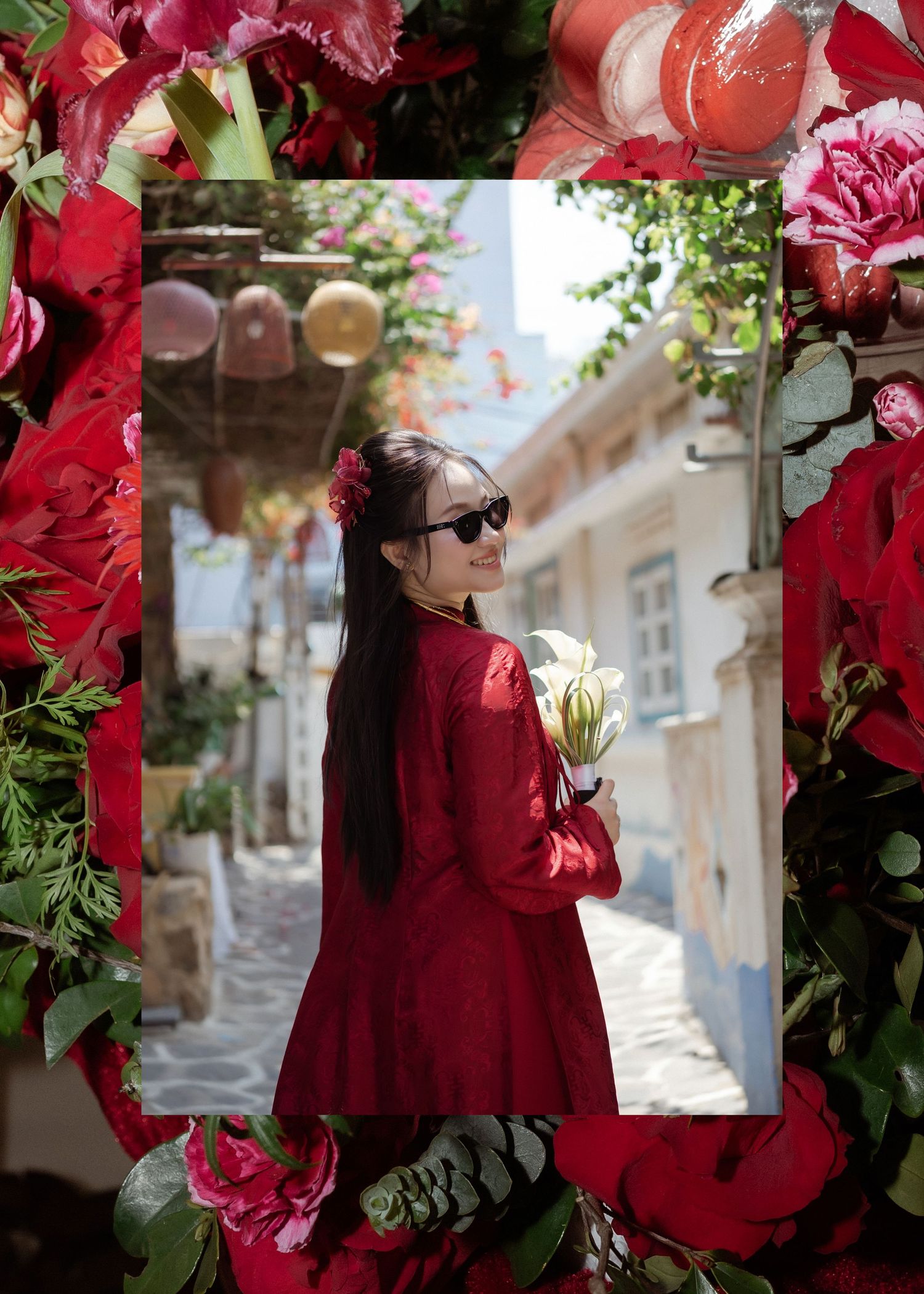 Elegant figure in a flowing red coat poses on a charming cobblestone street framed by vibrant red roses and paper lanterns.