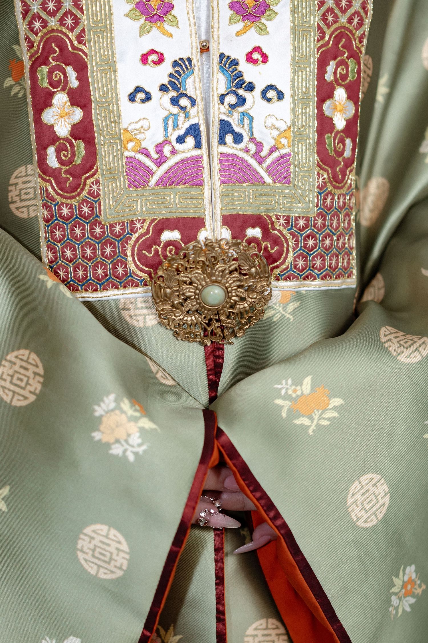 Close-up detail of traditional Korean hanbok showing ornate embroidery, decorative medallion, and floral patterns.